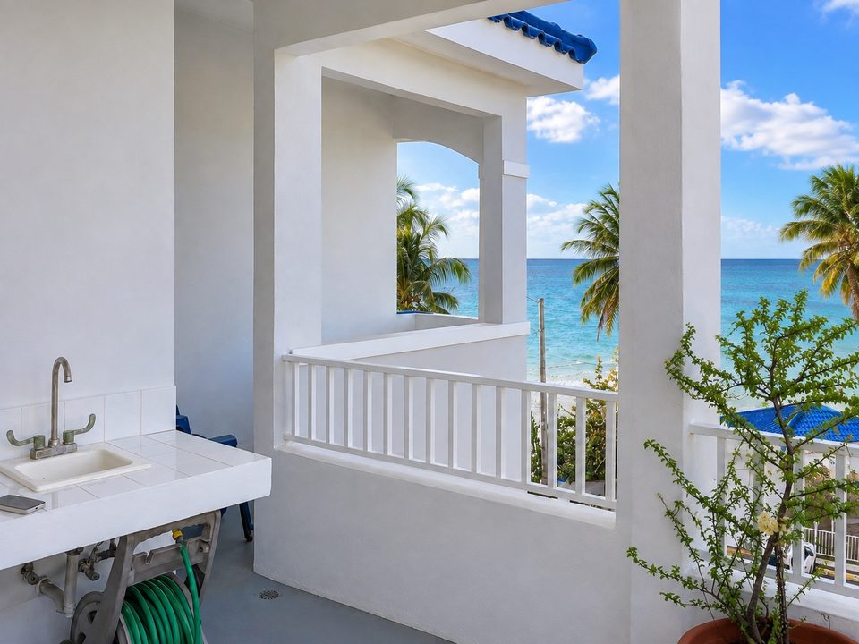 The balcony's outdoor sink and white railing, palms and the Atlantic beyond