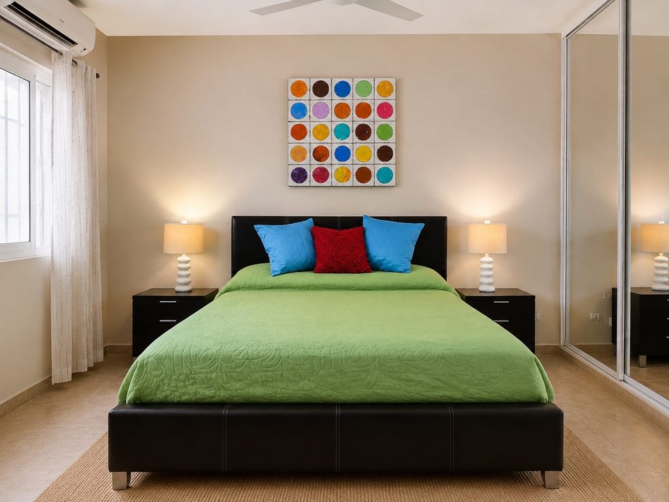 Bedroom two with a green quilt, colourful pillows and mirrored closet doors