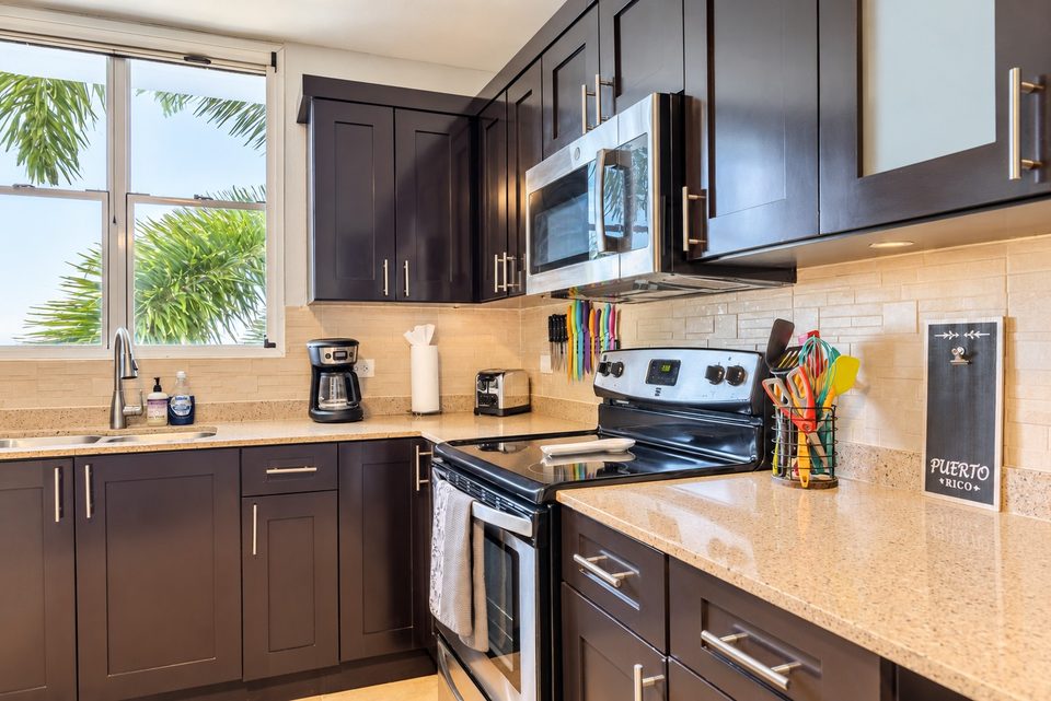 Stainless range and over-range microwave, stone backsplash, the corner window with palms outside