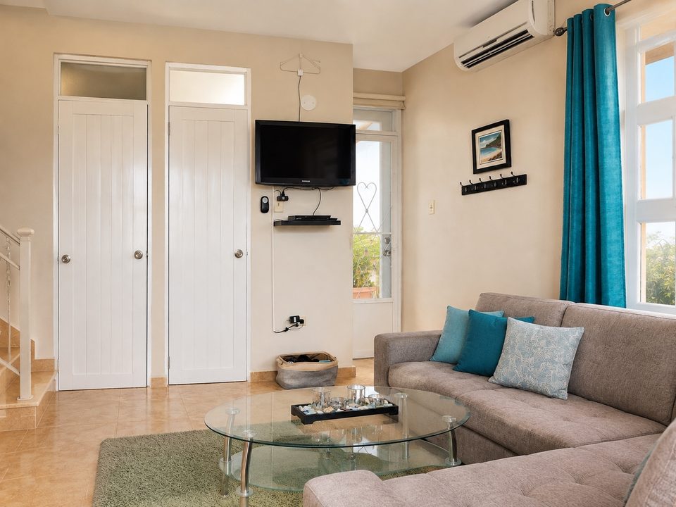 The living room entry with the wall-mounted TV, glass table and turquoise curtains
