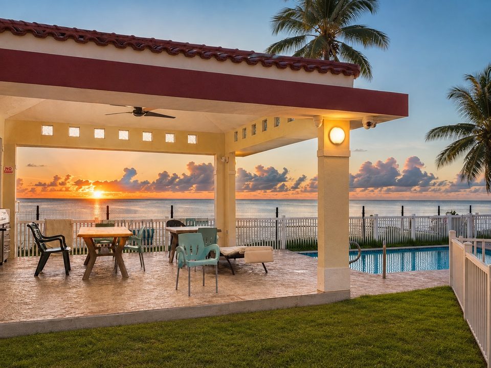 The poolside gazebo at sunset, tables and chairs, the lawn and the pool beside it
