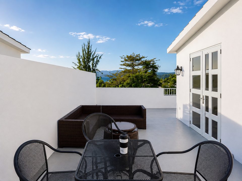 A bistro table and chairs on the white rooftop terrace, lounge seating behind